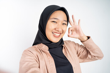 Asian woman in hijab holding a smart phone for selfie or video call on isolated background