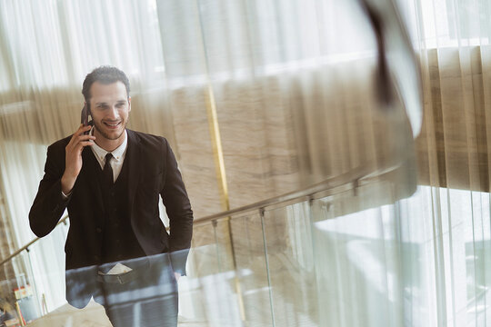 Portrait of modern businessman wearing formal suit going up spiral staircase in office building.