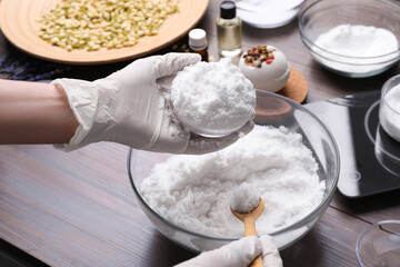 Woman in gloves making bath bomb at wooden table, closeup