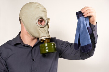 A man in a gas mask holds dirty smelly socks. The problem of unpleasant foot odor in men