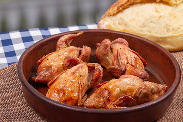 Close-up photo of roasted quail and white bread. Rustic style.