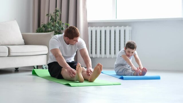 father and son are doing push-ups and having fun at home. diverse family. Sporty toned dad and boy child follow healthy lifestyle exercise taring together. Sport concept.