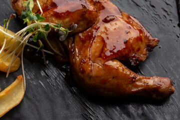 Grilled quail carcass with french fries on plate over black stone background. Roasted quails on plate. Top view, flat lay