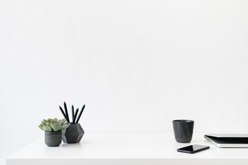 Office table, empty desk with supplies, mobile and white wall copy space.	

