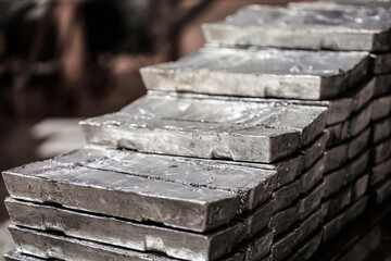 Close-up of a pile of zinc ingots. Raw materials for the smelting industry. Aluminum, tin, iron. Rough metal bricks. - obrazy, fototapety, plakaty