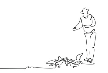 a person stands and feeds the birds on the ground