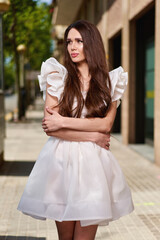 Young beautiful girl posing outdoor, wearing fashionable white dress. Summer style.