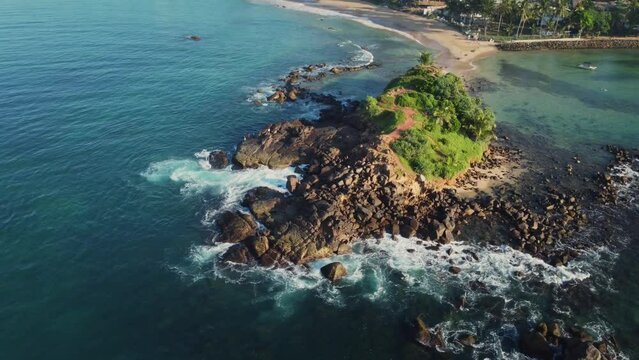 Deserted rocky tropical island in the middle of the beach at sunrise, Aerial 4K