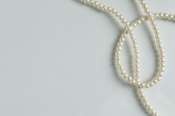 Elegant pearl necklace on white table, top view. Space for text