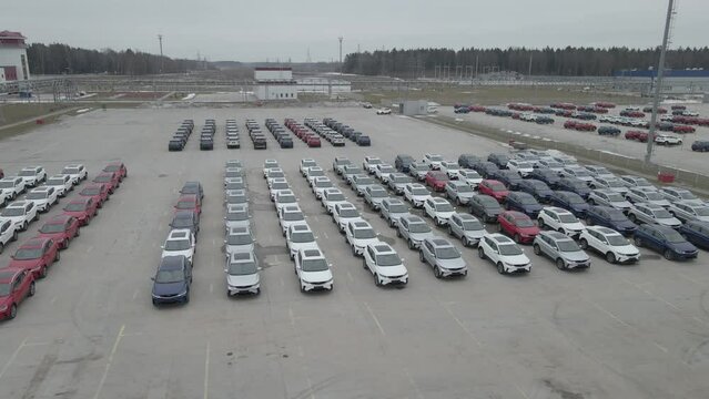 The new cars are lined up in the parking lot outside the production facility.