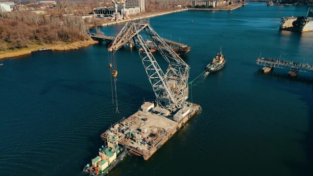 Tugboat pulls floating crane along river to shipyard in Nikolayev Ukraine few days before start of armored invasion. Logistics concept of water cargo transportation