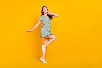 Fototapeta na wymiar Photo of pretty charming lady dressed green dress dancing smiling looking empty space isolated yellow color background