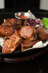 Grilled pork with baked golden potatoes served with red sauce on a dark background. Delicious Recipe. Pork Fillet Cooked