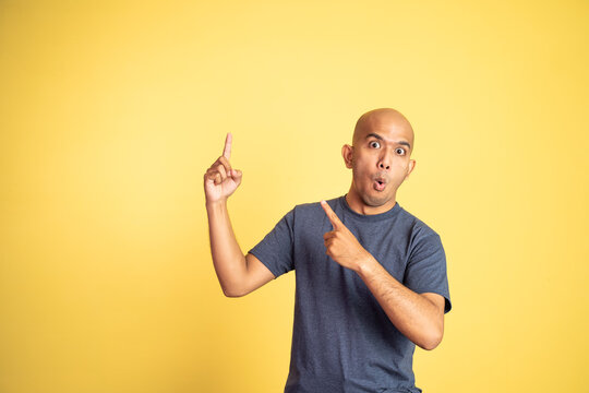 Excited Asian Bald Man With Two Fingers Pointing Up On Isolated Background