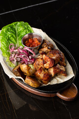 Grilled pork with baked golden potatoes served with red sauce on a dark background. Delicious Recipe. Pork Fillet Cooked
