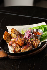 Grilled pork with baked golden potatoes served with red sauce on a dark background. Delicious Recipe. Pork Fillet Cooked