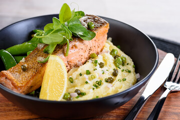 A serving of grilled salmon on a bed of mash potato and green beans.