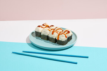 Baked Maki roll with shrimp and cheese on ceramic plate. Hot sushi roll with cheese topped on coloured background. Japanese menu concept. Hot sushi roll in modern style.