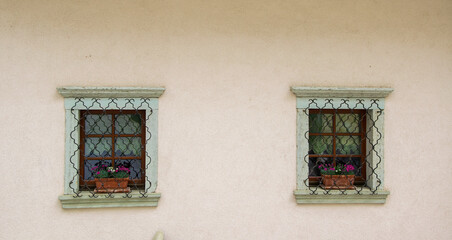Two latticed windows with flowerpots in old house in the center of Radovljica town, Slovenia