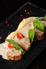 Baked meat and mashed potatoes as a garnish in white plate. Macro close-up on a black background. Delicious meal, restaurant menu concept.