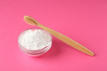 Fototapeta na wymiar Bowl of tooth powder and brush on pink background