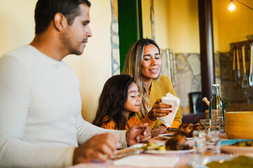 Latin parents having fun with their daughter during home dinner - Focus on mother face