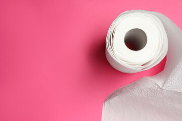 Roll of white paper towels on pink background, top view. Space for text