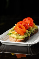 Buckwheat bread toast with an egg, a sliced avocado, a salmon, tomatoes and lettuce. Dietary menu. Flat lay.
