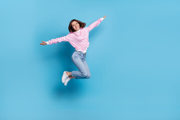 Fototapeta na wymiar Full size photo of impressed young lady jump wear shirt jeans sneakers isolated on blue background