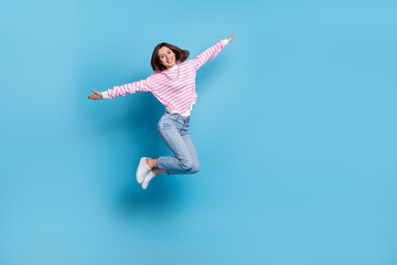Obraz premium Full size photo of impressed young lady jump wear shirt jeans sneakers isolated on blue background