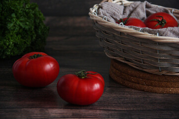 A basket with ripe juicy pink tomatoes and a bunch of parsley