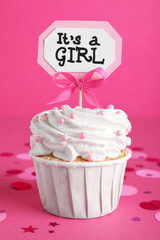 Beautifully decorated baby shower cupcake for girl with cream and topper on pink background