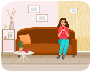 Woman sitting on sofa holds smartphone in her hand. Casual lady in headpones listening to music and browsing social media on mobile device. Girl on couch uses phone for chatting and surfing internet