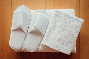 Flat lay view of fresh clean soft white hotel towels and disposable pair of slippers.
