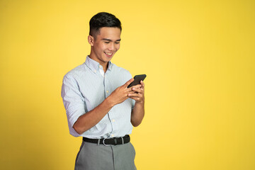 happy asian young man looking at the screen of a mobile phone on isolated background