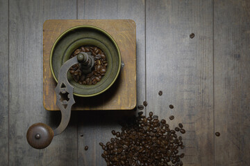 Old manual coffee grinder. Retro background with scattered coffee beans