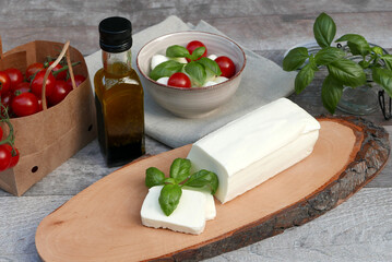 Mozzarella Käse mit Tomaten, Basilikum und Olivenöl auf einem Holztisch.