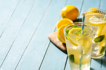 Glass of fresh lemonade on blue wooden background. Copy space