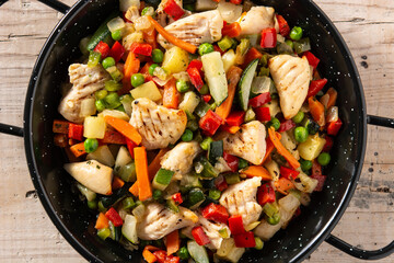 Chicken stir fry and vegetables on wooden table	