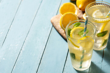 Glass of fresh lemonade on blue wooden background. Copy space