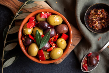 Delicious green and red olives with red chili pepper and olive tree leaves, healthy spicy appetizer
