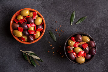 Delicious green and red olives with red chili pepper and olive tree leaves, healthy spicy appetizer