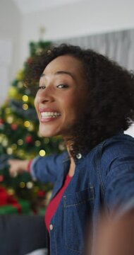 Vertical shot of an African American woman having a video call, smiling and waving at the camera
