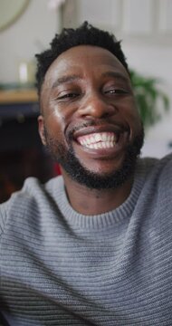 Vertical shot of an African American man having a video call, smiling and laughing