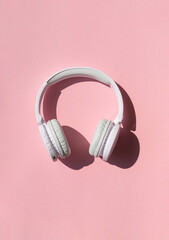 Wireless white headphones background on the pink close up. Listening to  music concept