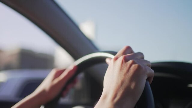Hands of the female driver on the steering wheel of the car. Traffic control in motion, close-up 4K 10 BIT