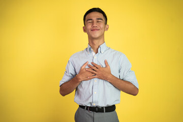 young man holding chest feeling relieve and comforting himself standing over white background
