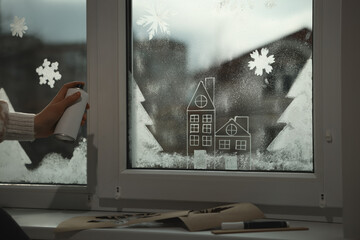 Woman using snow spray for decorating window at home, closeup