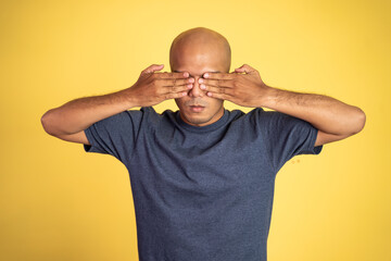 bald man with hands covering eyes standing with isolated background