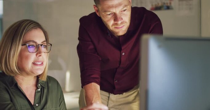 They're dedicated and committed to making it big. Two colleagues working late on a computer in an office. Businesspeople working overtime.